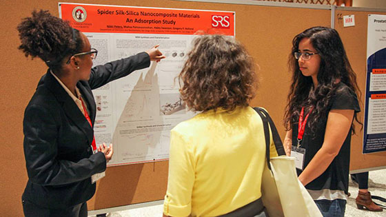 Student presents research poster to two students at Student Research Symposium