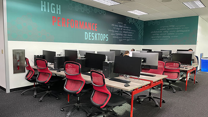 Rows of red chairs and high-performance desktop computers under a wall mural labeled “High Performance Desktops.”