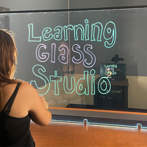 Student using the Learning Glass Studio with colorful handwritten text glowing on a transparent glass panel.