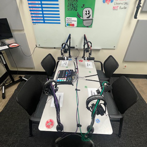 Multitrack podcasting setup with microphones and headphones at a table in a studio environment.